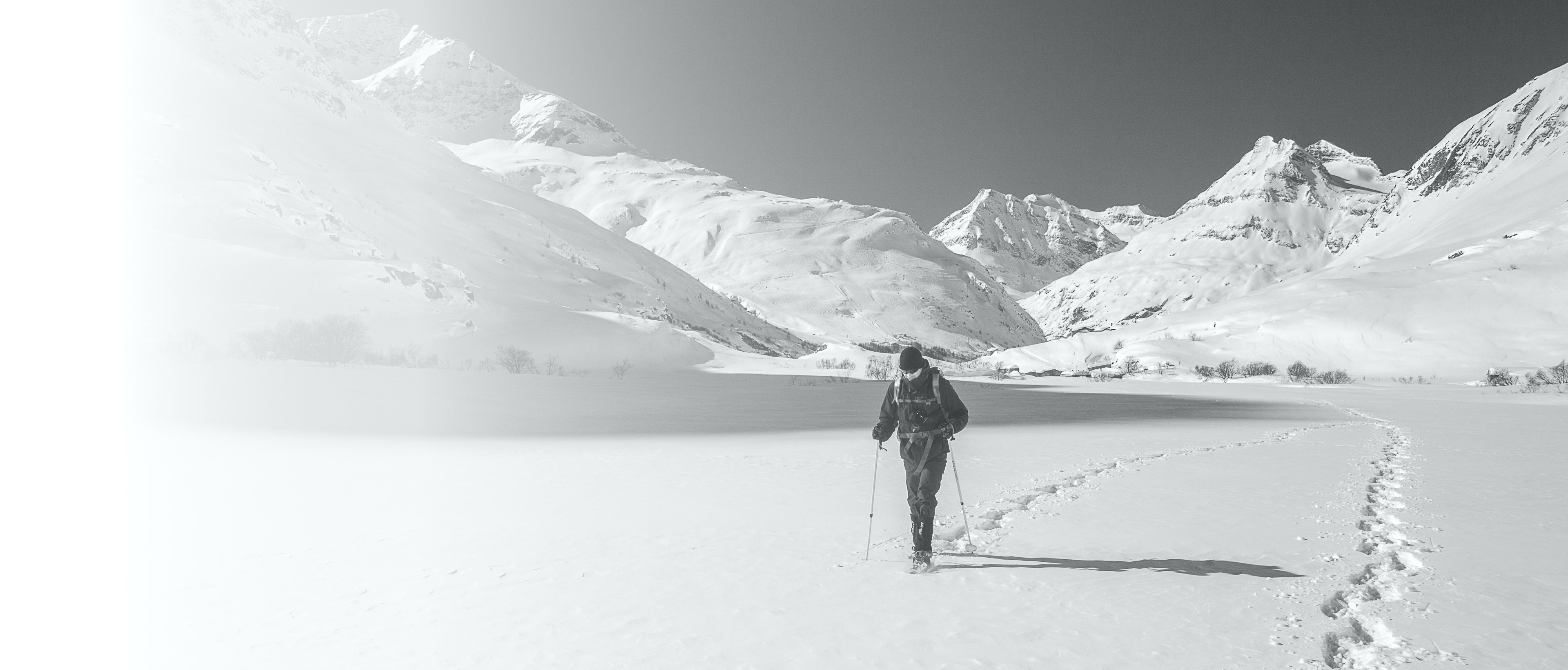 Ein Mann läuft durch den Schnee. Ihm wird von einer anderen Person der Weg gewiesen, aber er ist trotzdem auf seinem eigenen Weg